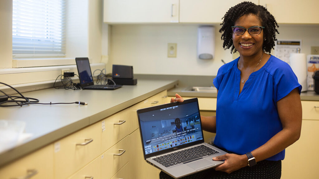 Basheerah Enahora is a doctoral candidate in the Department of Nutrition and a Minerva Scholar at UNCG. She is pictured with the nutritional program she adapted for her dissertation.