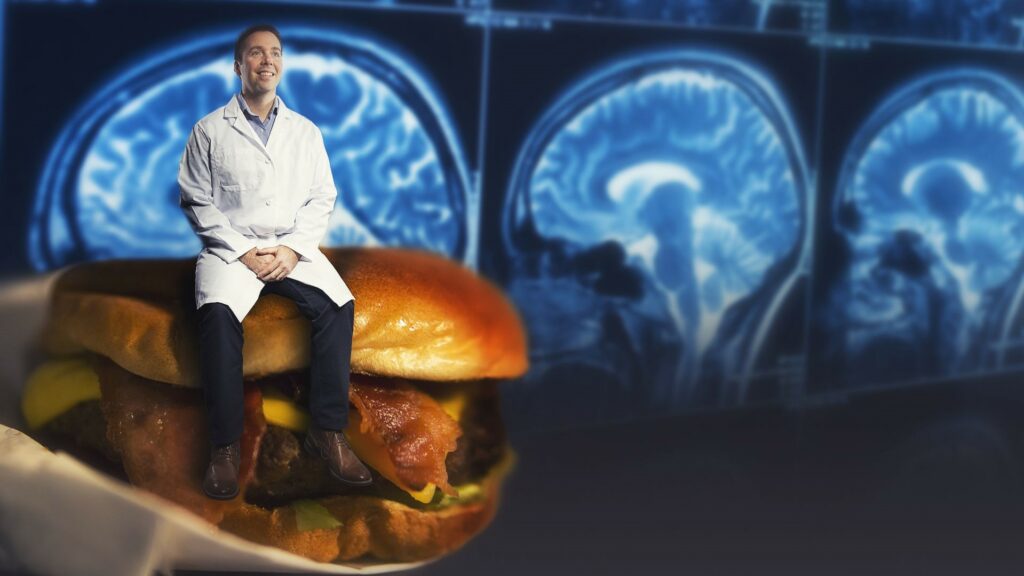 Scientist sitting on an oversized hamburger.